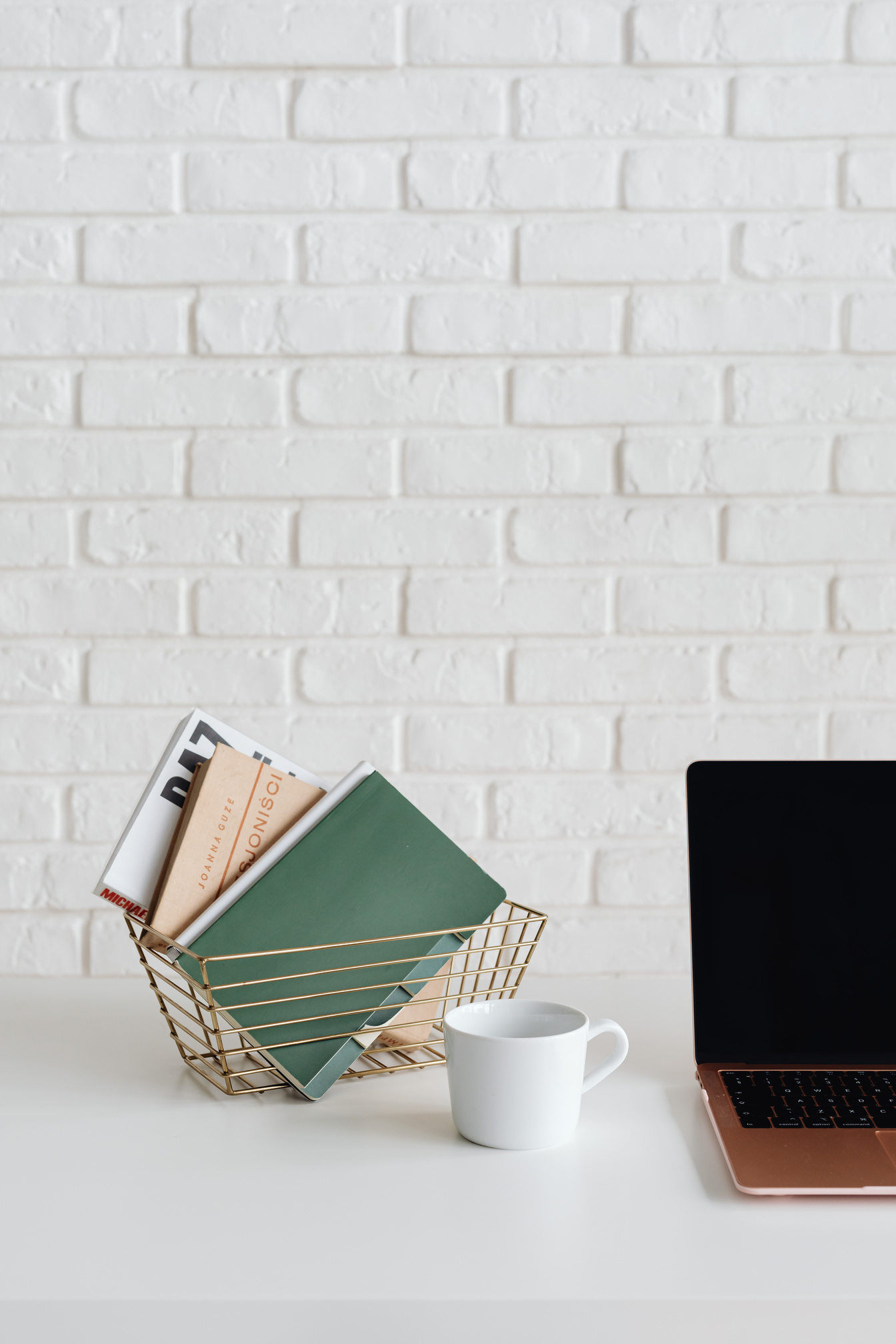 Notepads in Metal Basket on White Table Beside Laptop